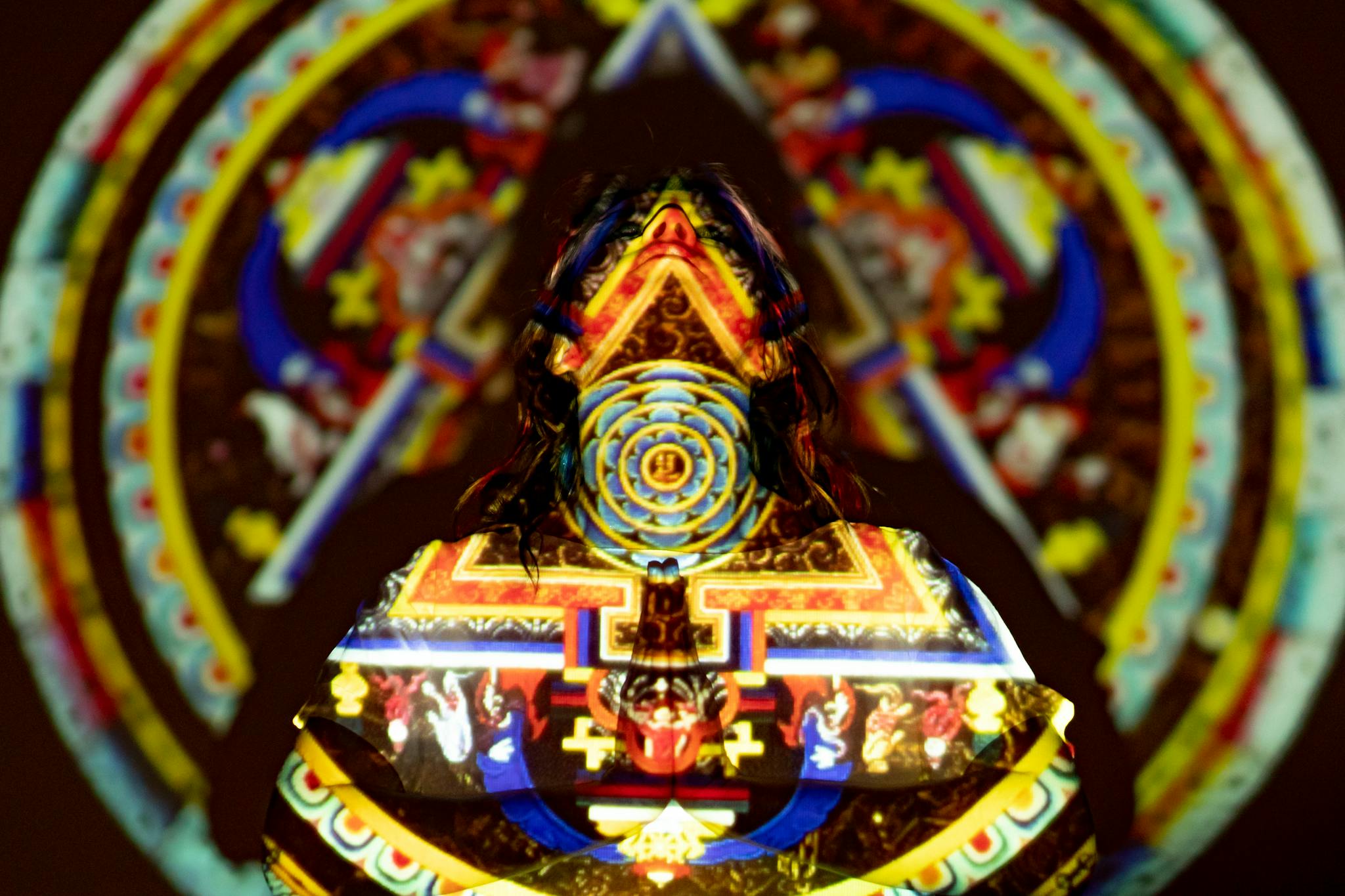 Vivid projection of a mandala on a figure, creating a colorful and mystic effect.